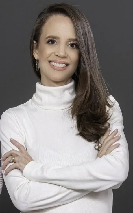 Lívia, da liderança da Automatize Projetos: cabelo castanho longo, blusa branca de gola alta, braços cruzados